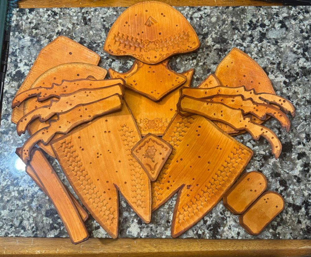 All the pieces for a leather beetle bag displayed. These pieces are now dyed a light brown with dark brown borders