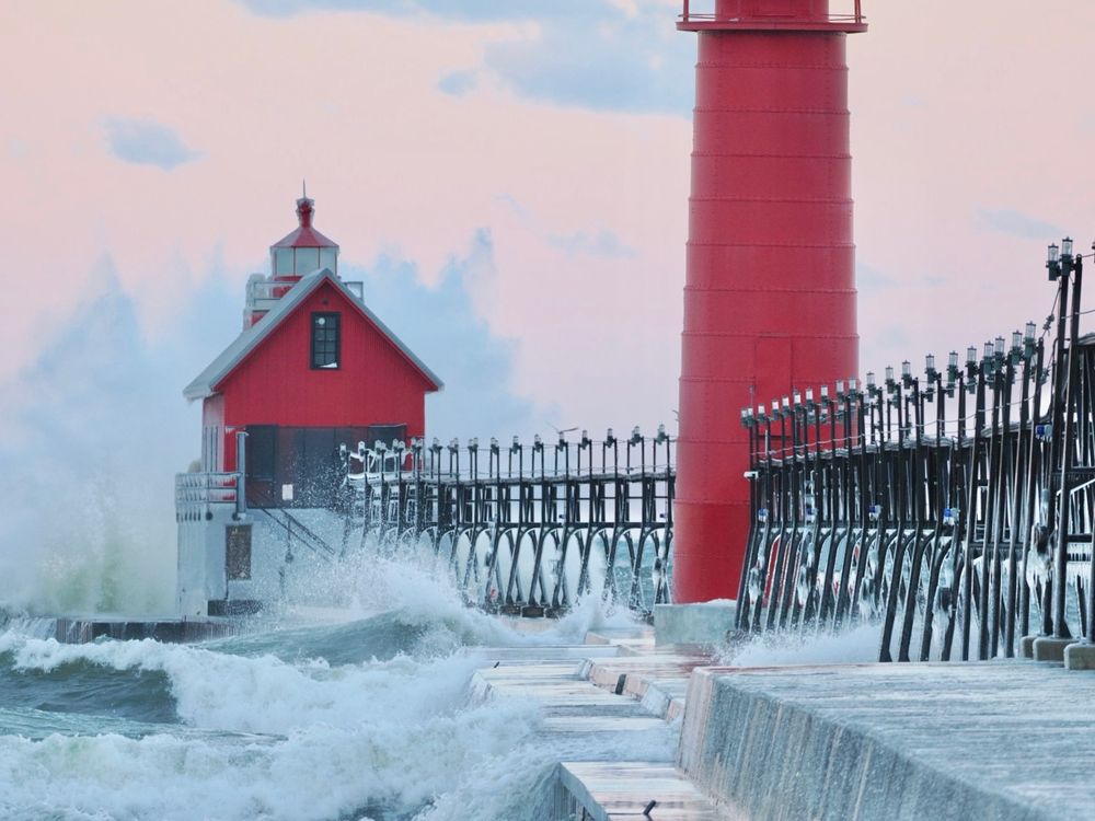 Monster waves crashing against a frozen red lighthouse on Lake Michigan.