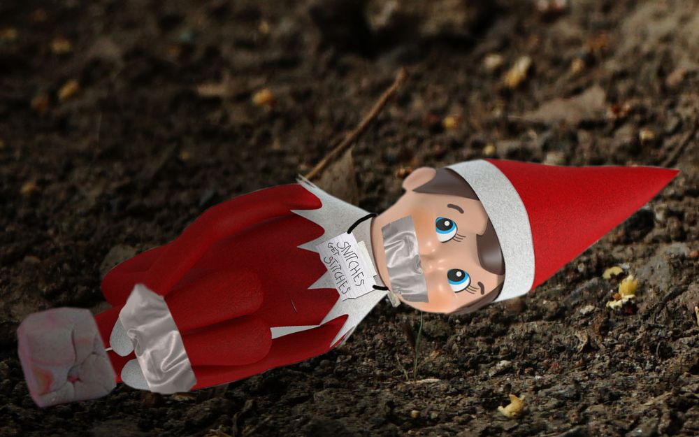 Tied-up Elf on a Shelf in a ditch with his mouth duct taped and a sign hanging from his neck reading "snitches get stitches" 