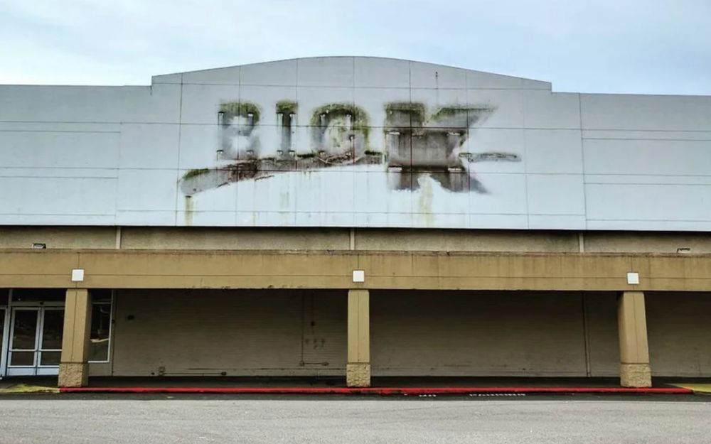 Abandoned K-Mart exterior with gritty marks of removed old K-Mart sign 