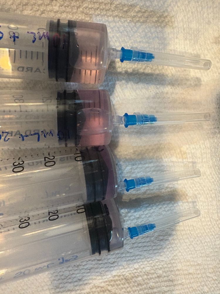 Four syringes with pink colored solutions
