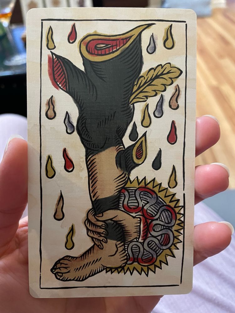 A ruffed hand grips a severed leg by the ankle like a baton. The leg seems to be sprouting branches, which have also been chopped off