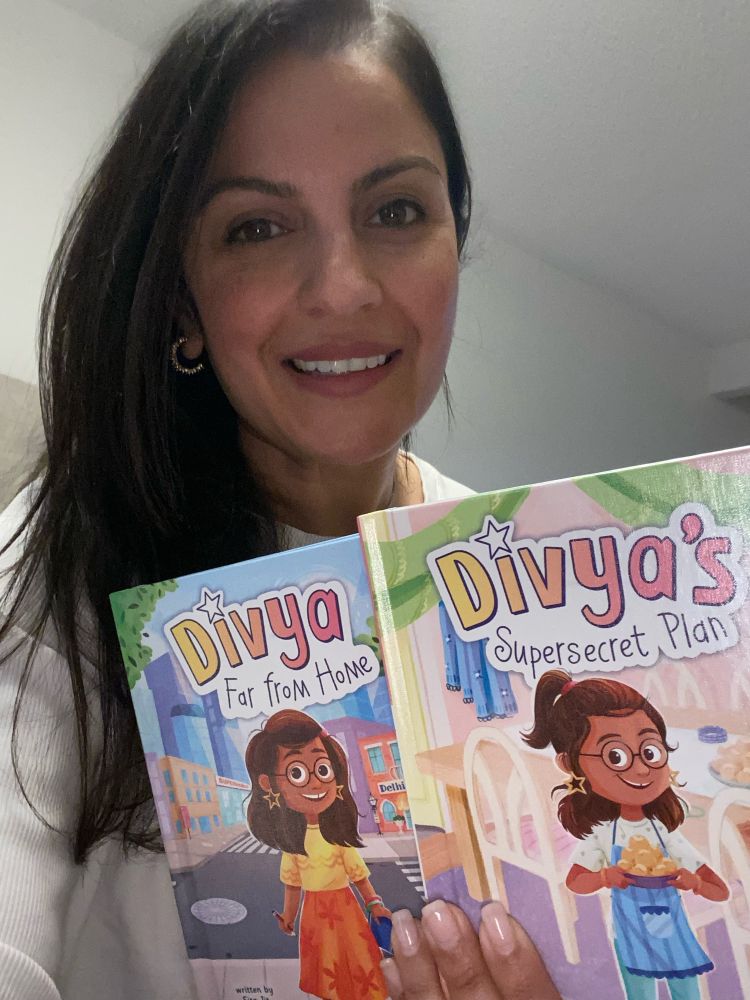 Author holding up two books, Divya Far from Home and Divya’s Supersecret Plan 