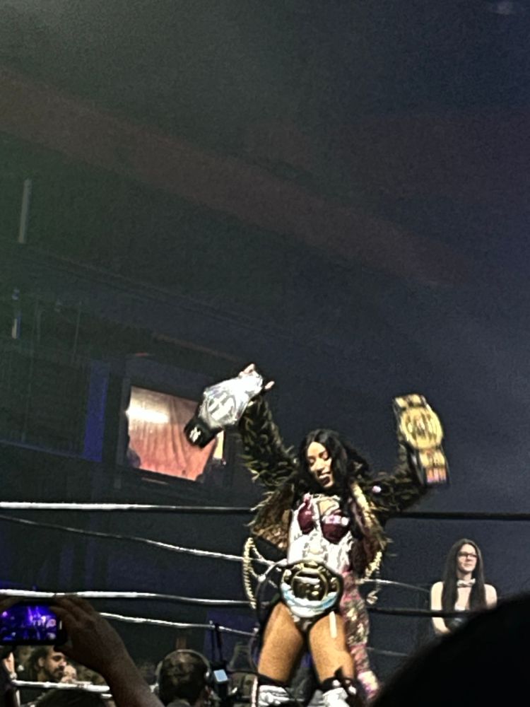 Mercedes Moné raises the RevPro Women’s title in the air while wearing her other four titles around her waist in a warehouse in Wolverhampton 