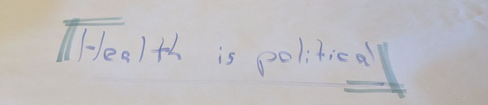  The message "health is political", handwritten with markers on a piece of butchers paper