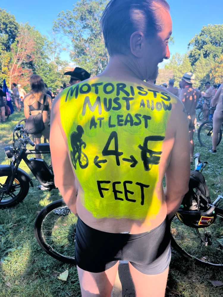 My back (I’m wearing a swimsuit, pretty sure nobody’s genitals visible in this photo) painted up like the PA-standard “motorists must allow at least 4 feet” road sign.