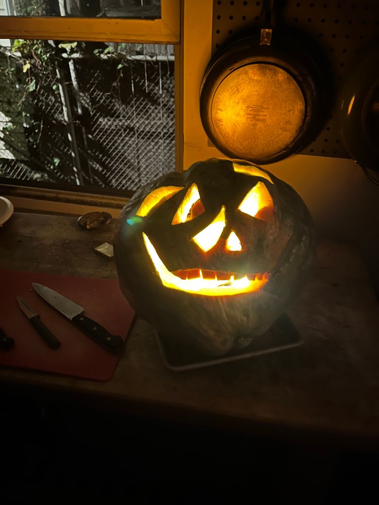 It’s a pumpkin with a grinning face carved into it, roughly adhering to the fruit’s growth lines.

Here lit with a bike headlight. 
