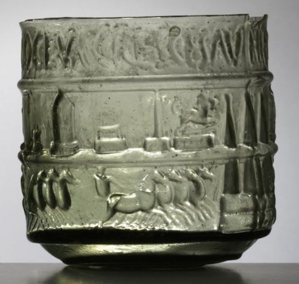 A green glass cup from the Roman Empire showing horses and monoliths