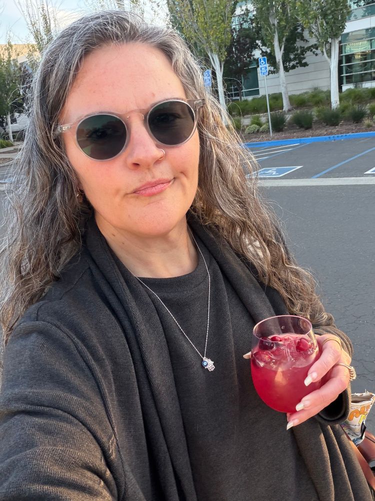 It's me I have long gray hair and I'm wearing a long gray cardigan and shirt and I'm in a parking lot holding a glass of cranberry lemonade 