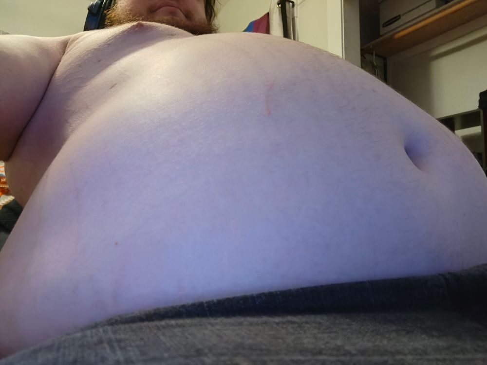 A very fat guy showing his stuffed, stretched belly off ;w;