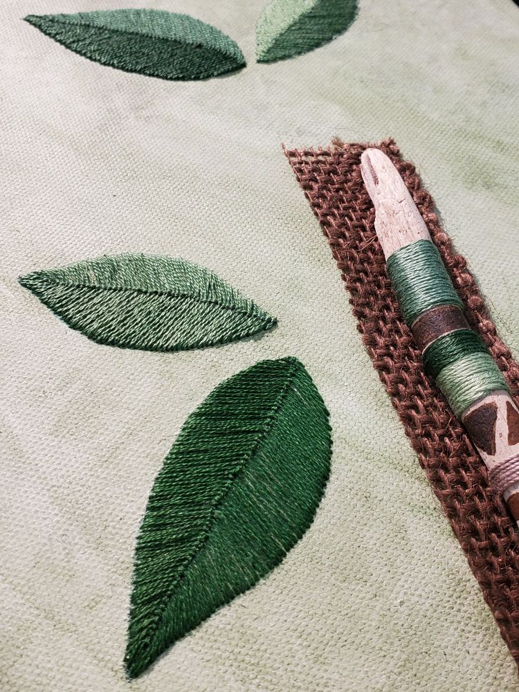 Detail of Fiber Art Mixed Media Collage Assemblage, Hand Stitched Green  Leaves on Green Acrylic Washed Canvas with Green and Brown Painted Yarn Wrapped Driftwood on Brown Burlap

Original Work by Amy C Lund 