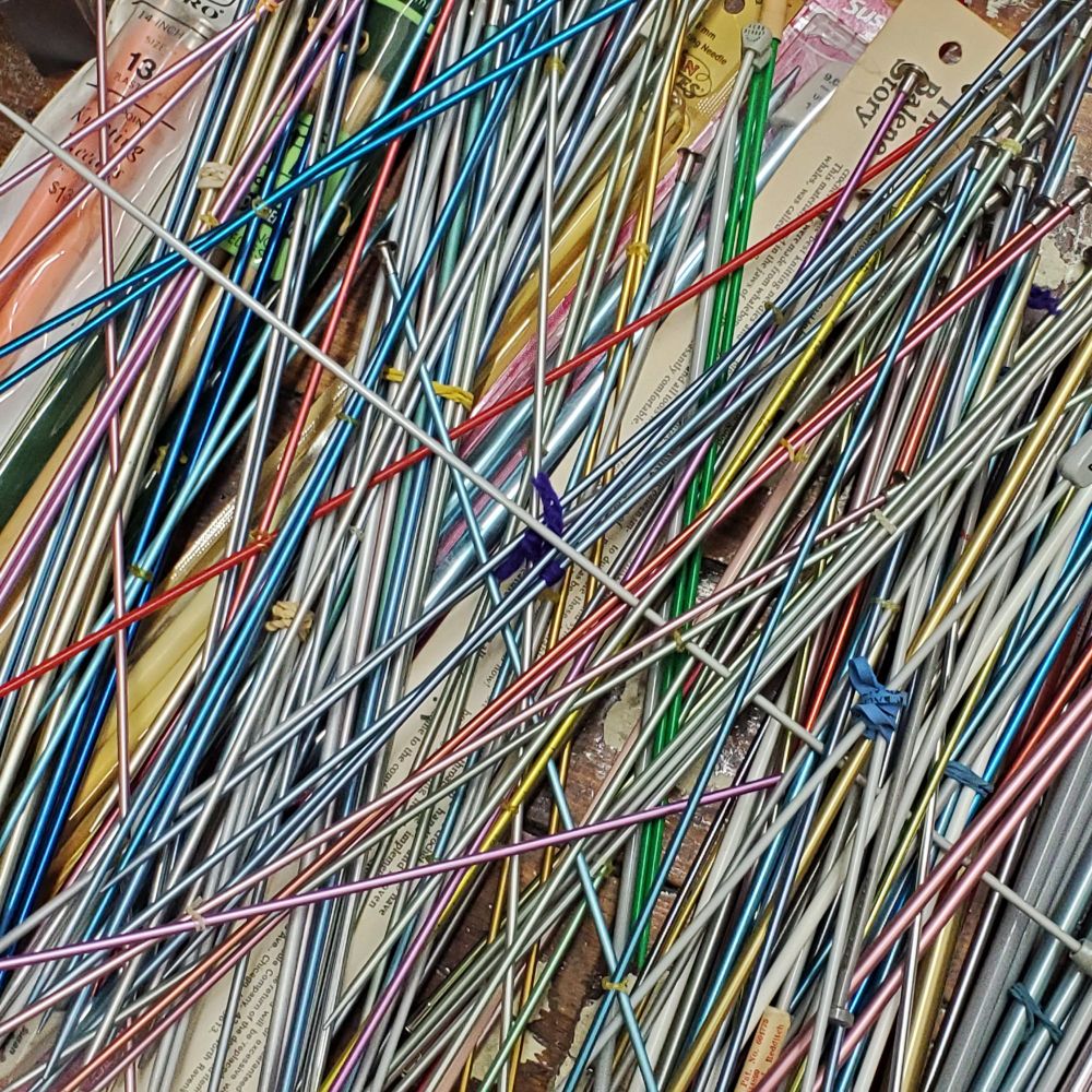 Colored metal knitting needles scattered like pick-up sticks.