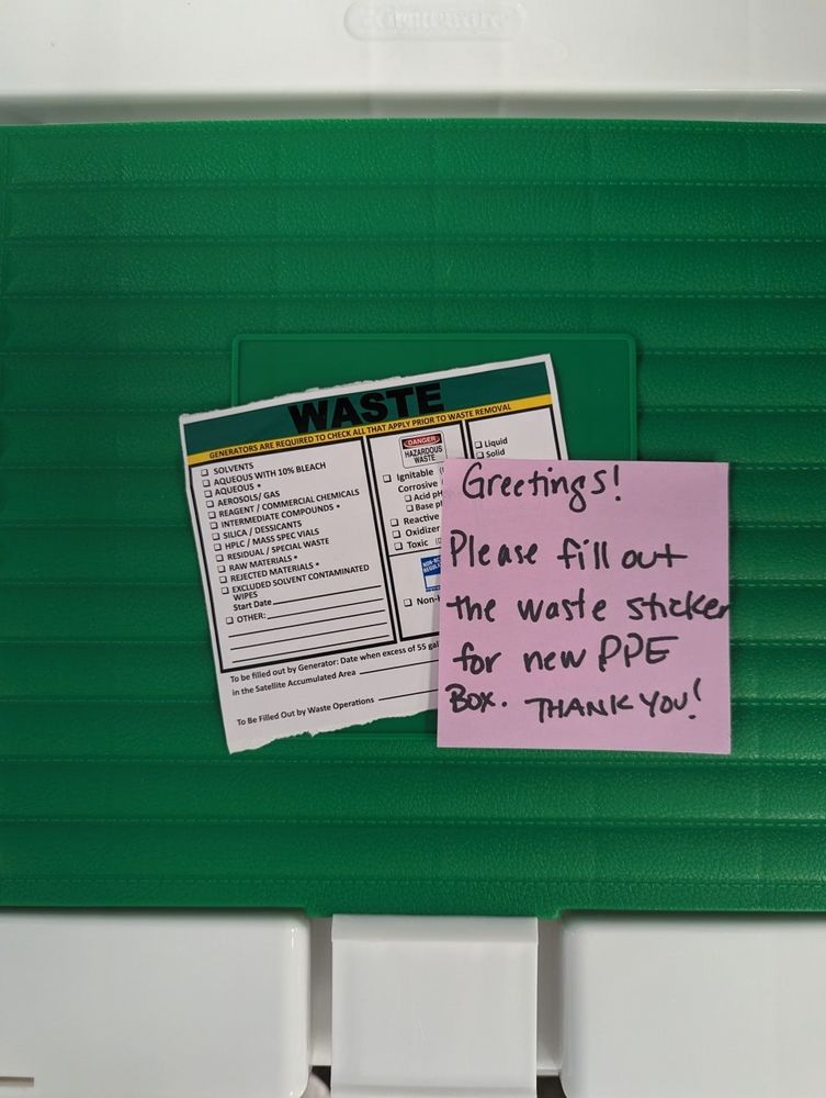 A post it note left on a new waste disposal sticker that says "Greetings! Please fill out a waste sticker for new PPE box. Thank you!" The note includes more writing than it would have taken to fill out the disposable sticker itself.