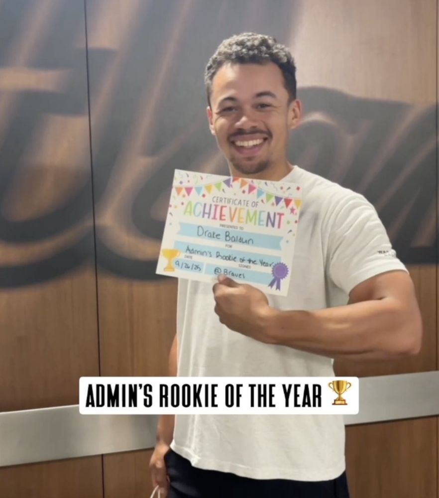 Drake Baldwin smiles with his certificate of achievement given to him from the social team reading "Admin's Rookie of the Year."