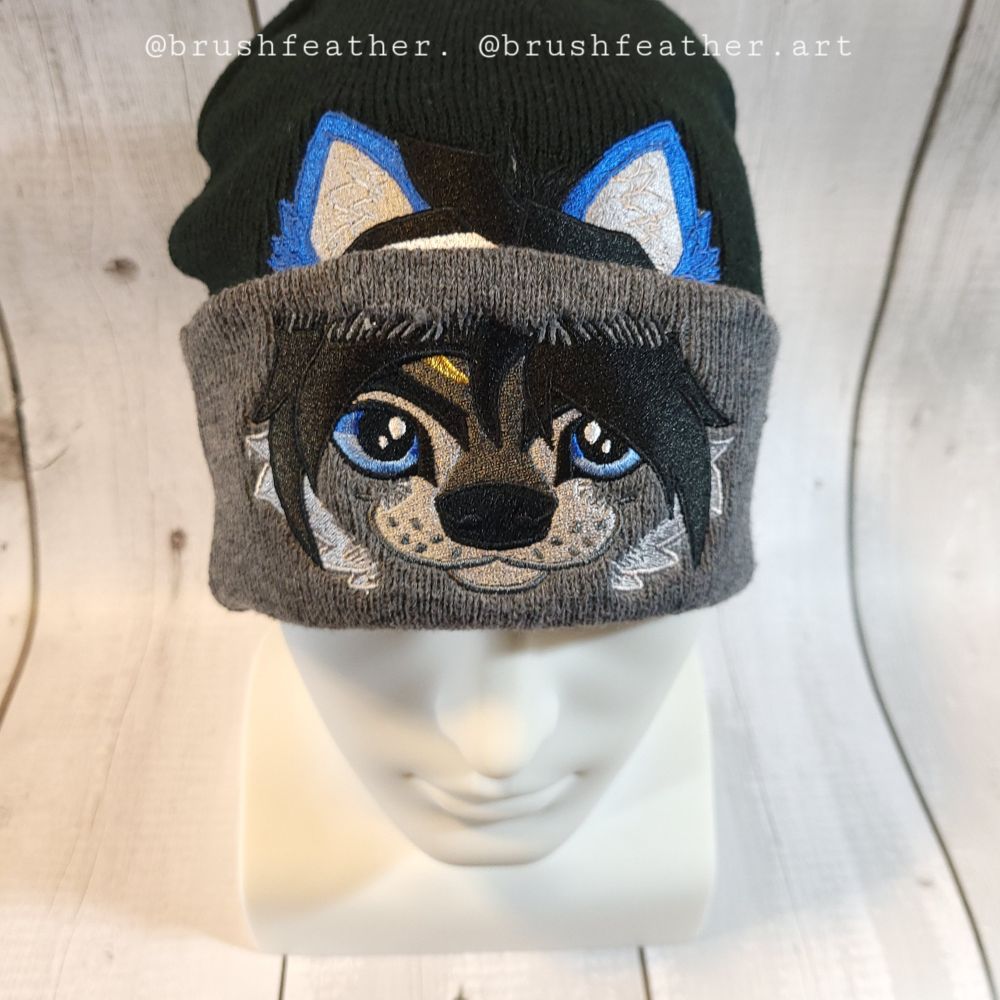 A custom embroidered gray and black hat with an anime-style wolf character in grays and blues. 