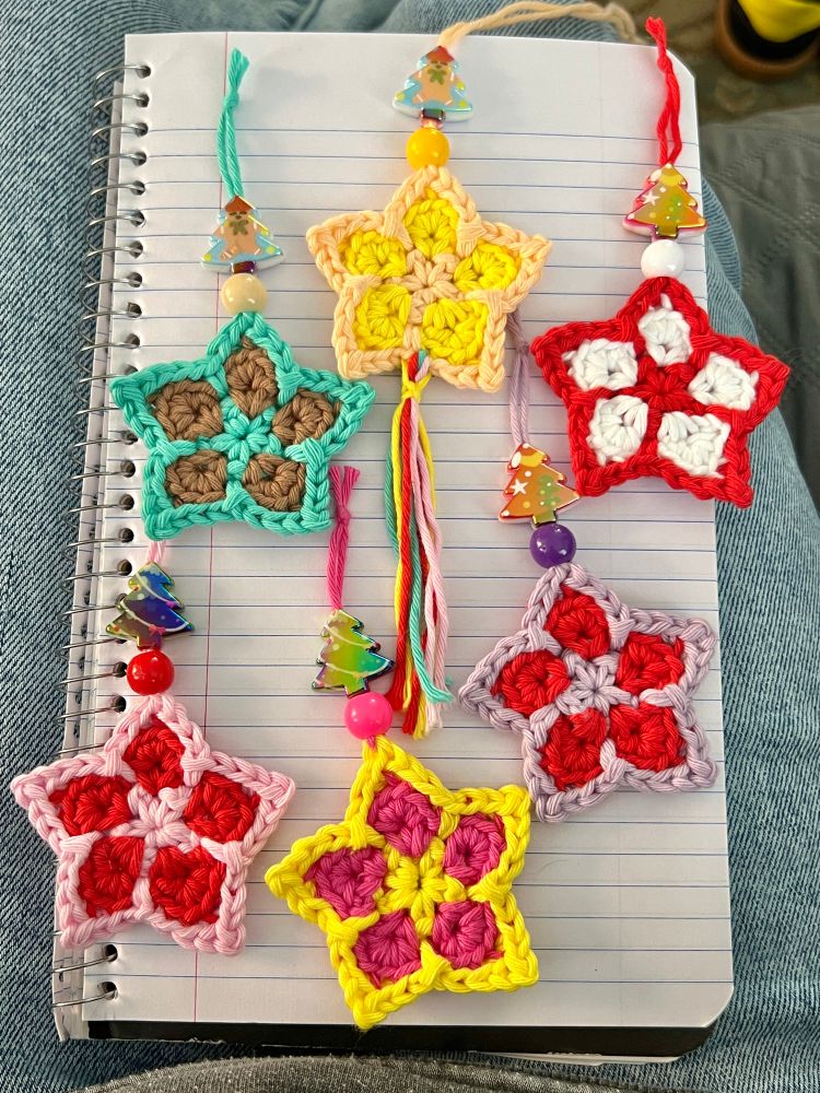 6 colorful crochet star ornaments on a notebook in my lap. 