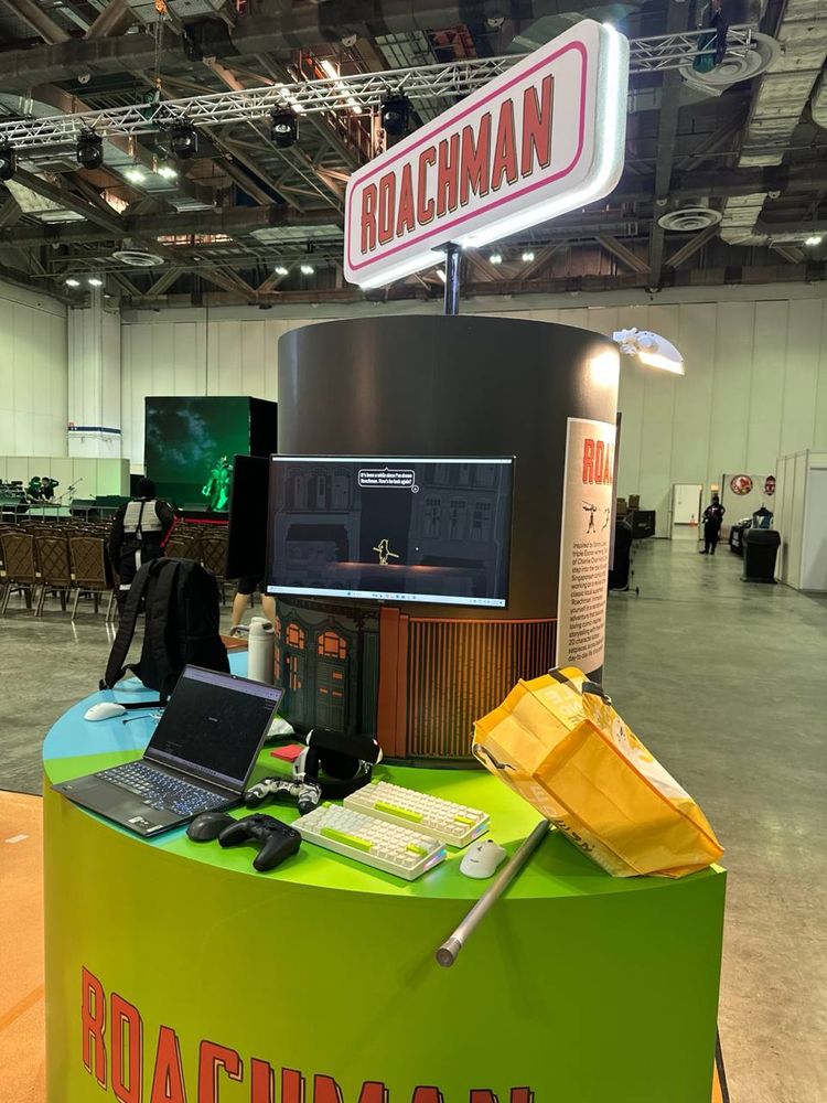 A con booth with a PC and controllers, with a sign above that says "ROACHMAN"
