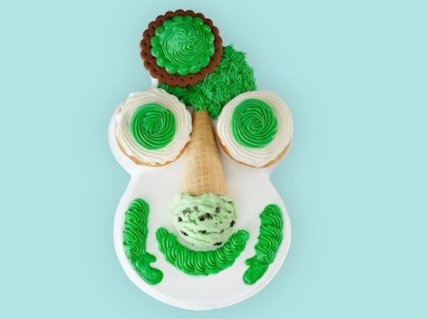 A carvel ice cream cake adorned in green frosting. His nose is an ice cream cone and his features are low level Picasso cubism. A masterpiece 