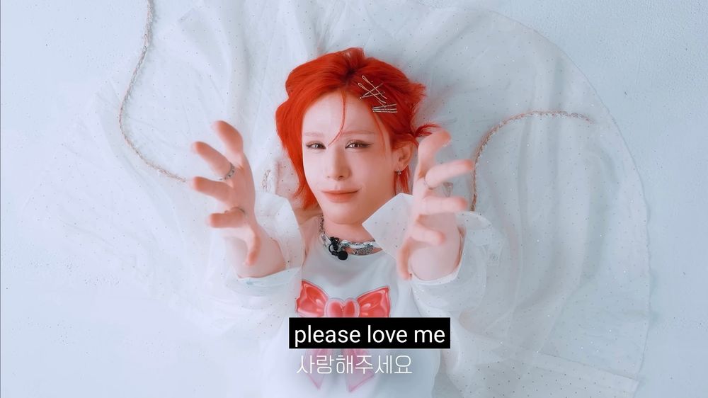 soft pastel wumuti smiling up at the camera with both arms extended upwards. the caption reads, "please love me"