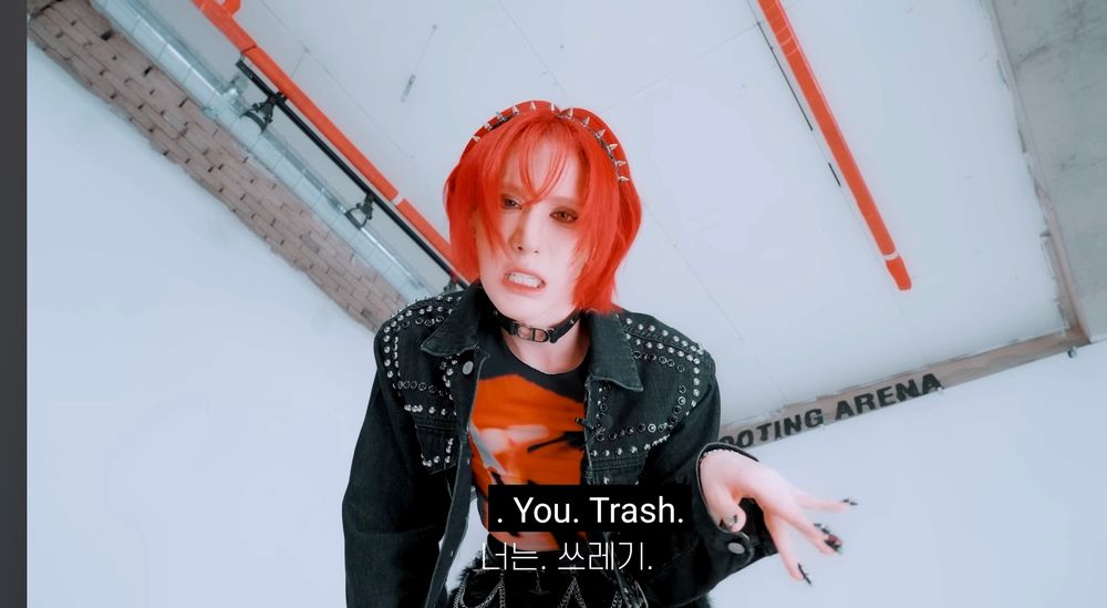goth-lite wumuti glaring down at the camera with bared teeth, waving a dismissive hand. the caption reads, "you. trash."
