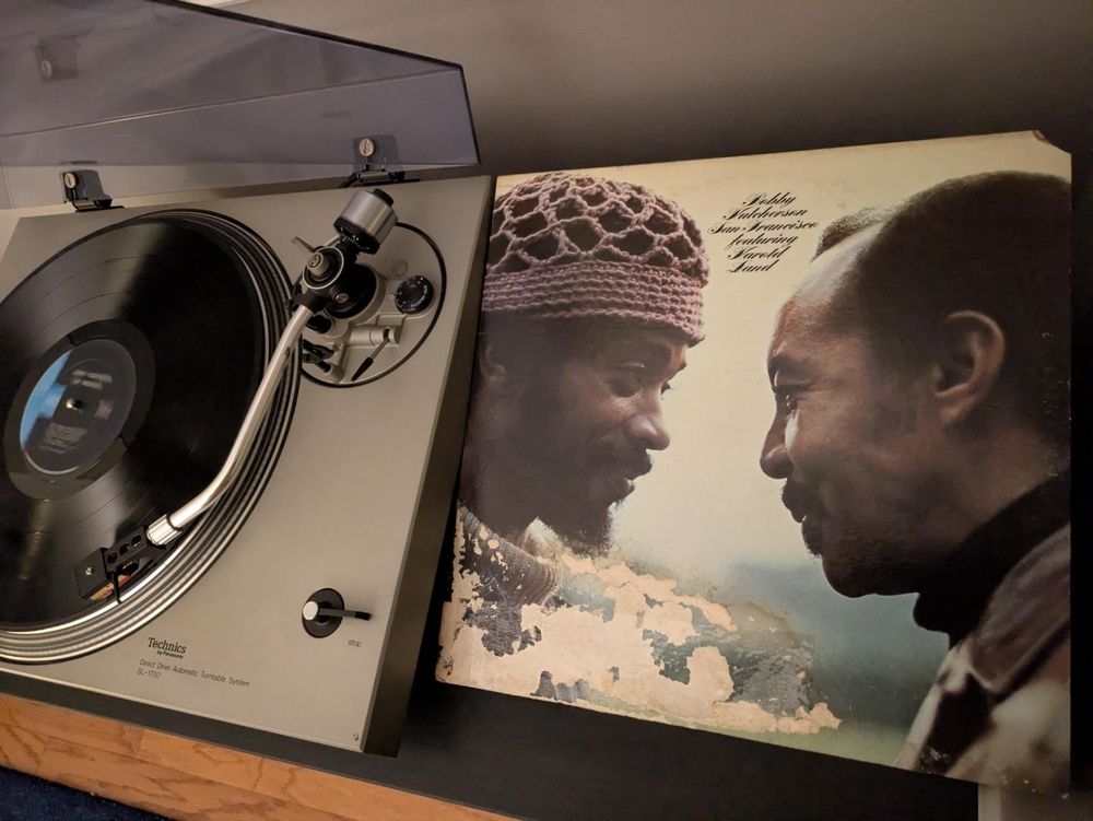 record playing on a turntable next to album cover with photo of Hutcherson & Land looking into each other's eyes