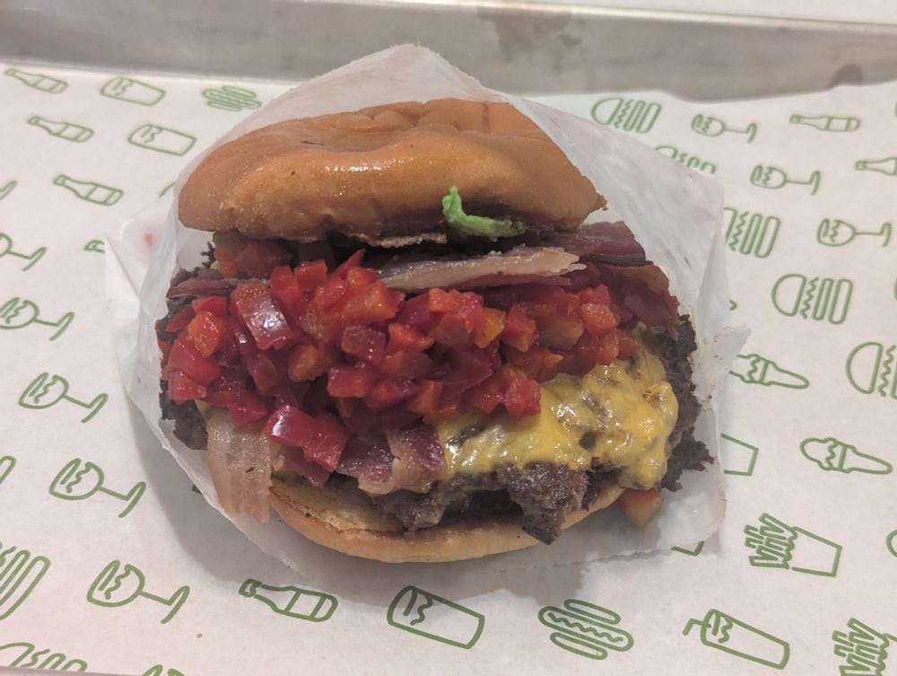 A bacon cheese burger absolutely loaded down with chopped cherry peppers