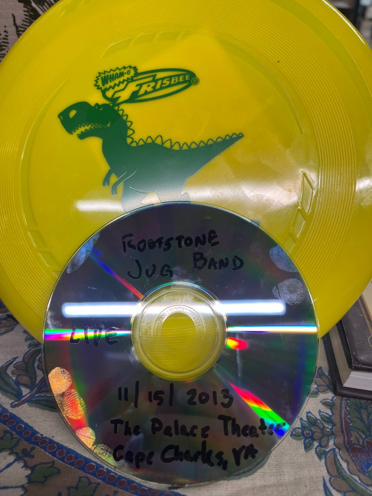 Frisbee with a dinosaur on it, with a CD-R containing a 20 song show from 2013 by Rootstone Jug Band. 