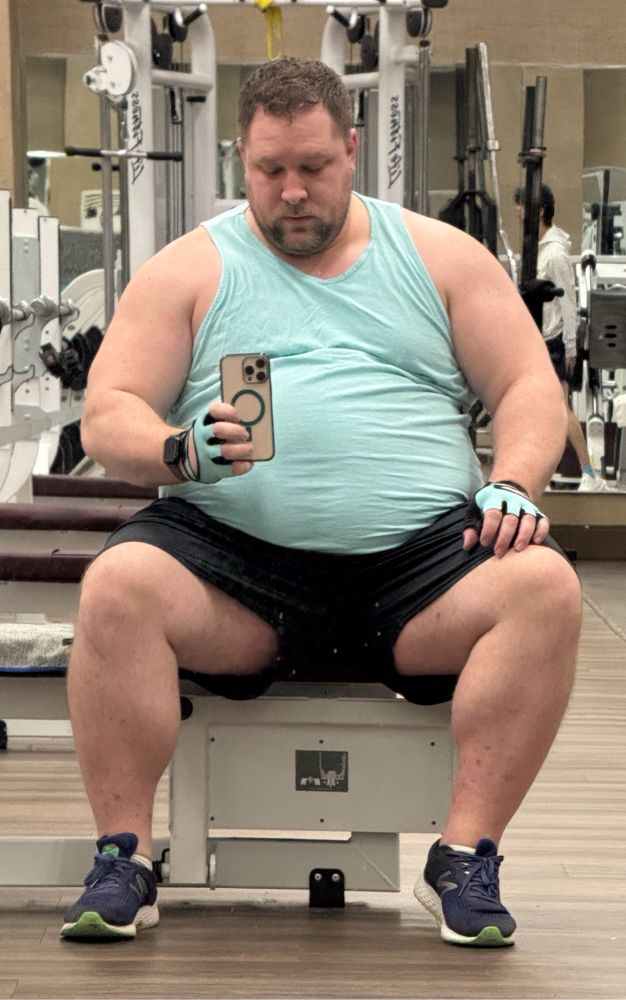 Man in a light blue tank top sitting on a bench