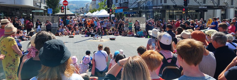 The crowds watch street entertainers.