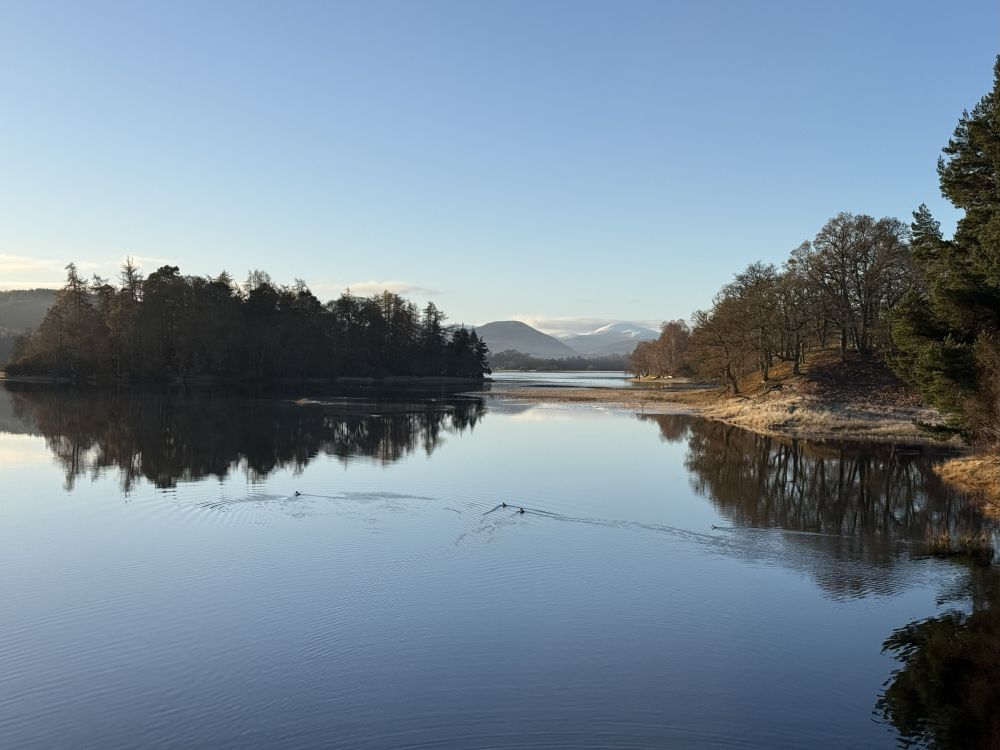 Still loch with distant mountains and sunshine