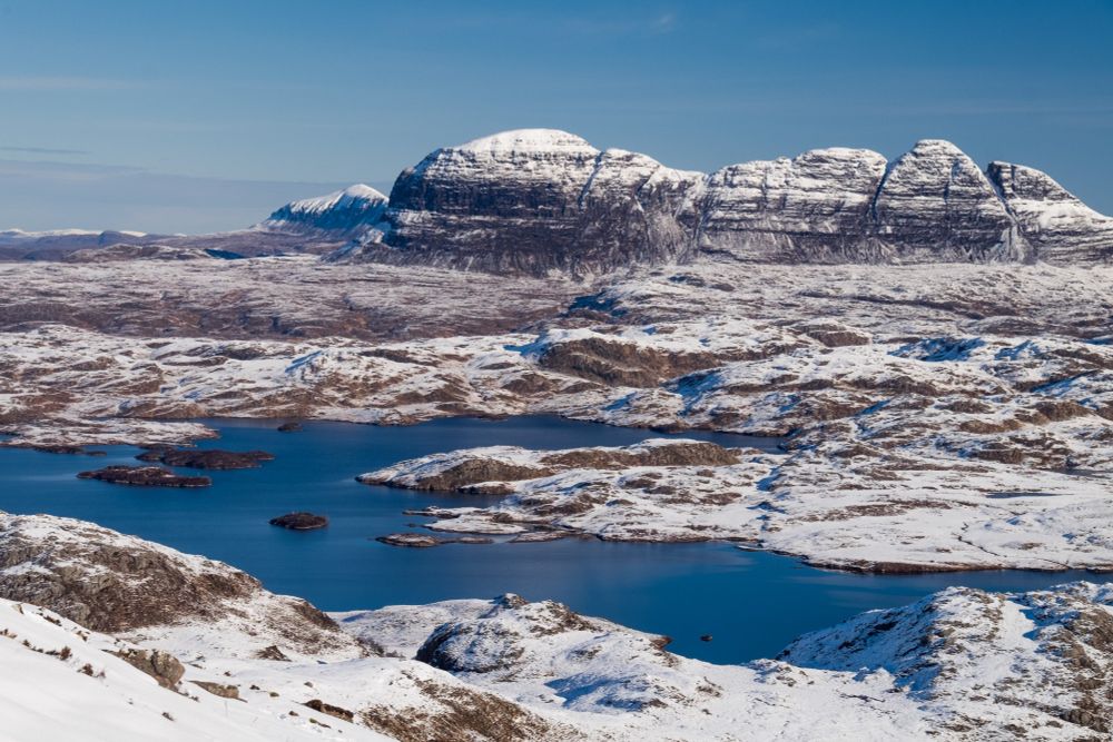 Mountain seen beyond loch, in a snow-dusted landscape