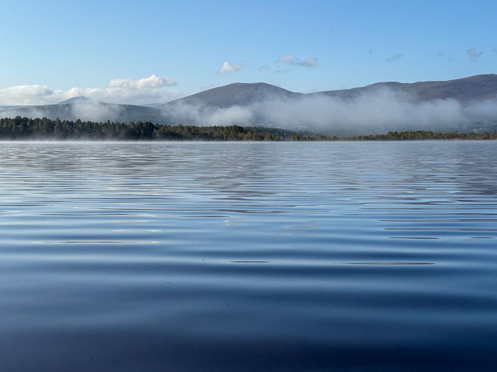 Ripples on loch surface with misty hills beyond