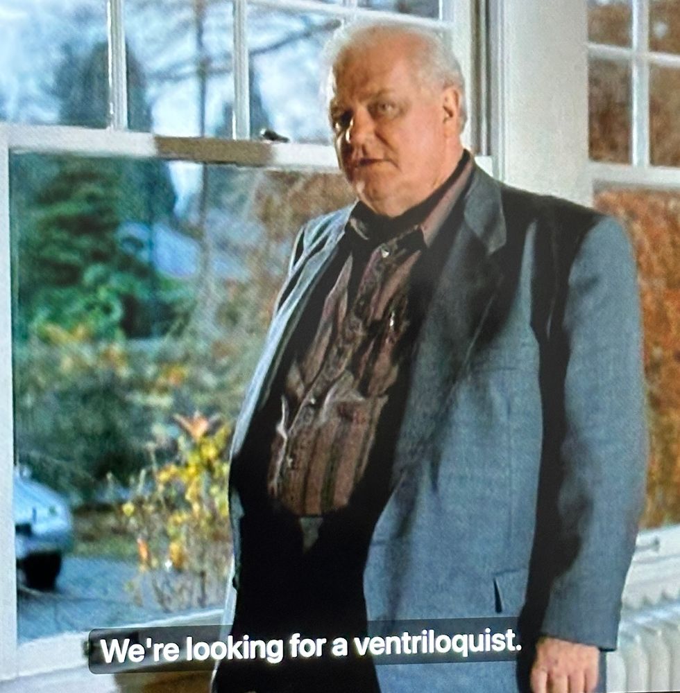 Charles Durning in When a Stranger Calls Back. He is standing in front of a window saying “We’re looking for a ventriloquist.”