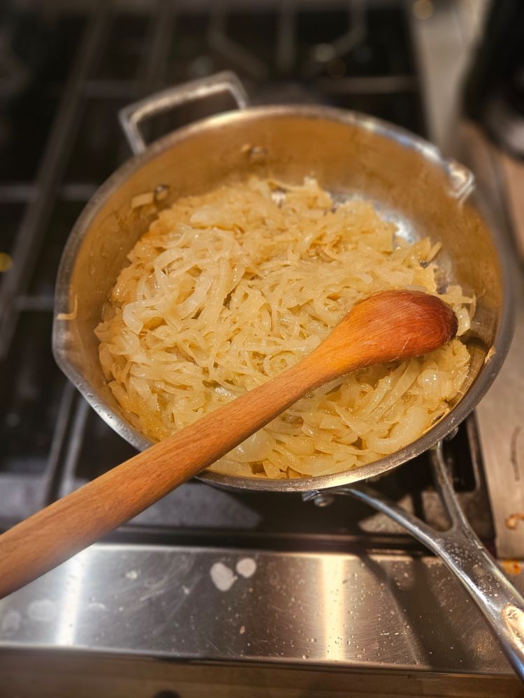 3 blonded onions and a spoon in a saucepan
