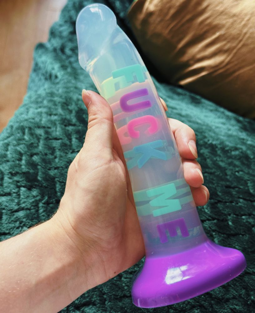 image of bingo’s hand holding a large clear dildo with a purple base, with the text „fuck me” at its core