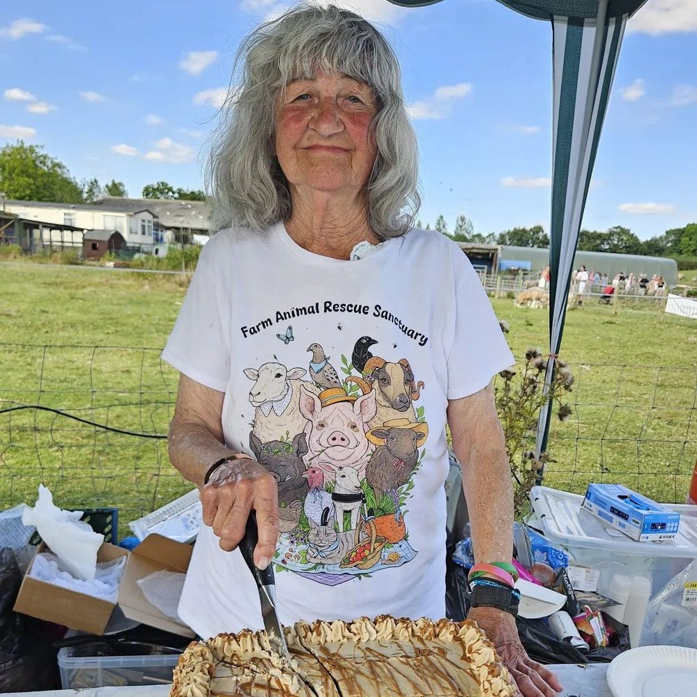 A photo of Carole Webb cutting a cake at FARS vegan fair in August 2024