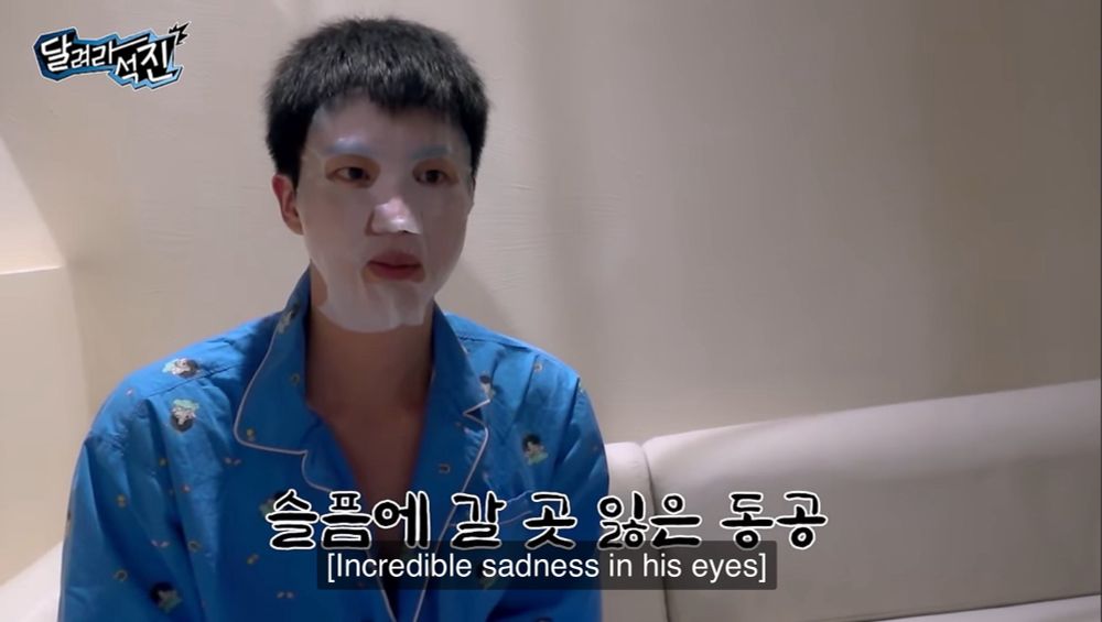 Kim Seokjin of BTS wearing a sheet mask and pjs with a despondent expression. The subtitles read “incredible sadness in his eyes”