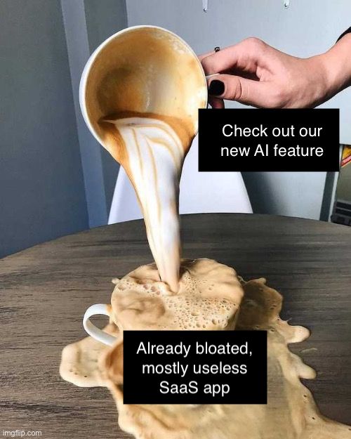 There's a latte on a wooden table in a wide, shallow cup. A person is pouring another latte into that original one, causing loads of overspill. 

The original latte is captioned "Already bloated, mostly useless SaaS app" and the pouring latte is captions "Check out our new AI feature"