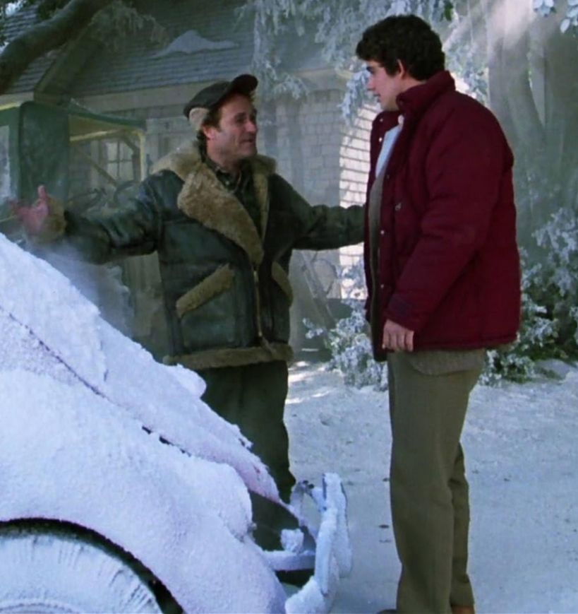 Photo: Murray Futterman (Dick Miller) and Billy Peltzer (Zach Galligan) from Gremlins (1984). Murray stops the younger Billy outside his home to discuss the inclement weather conditions affecting their town because Murray is a self-employed snow plow operator. Notably, Murray wears a bomber jacket, a popular clothing item in the years during and after the Second World War.