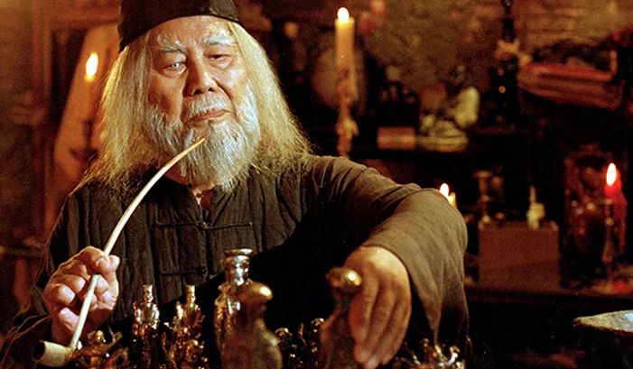 Photo: Mr Wing (Keye Luke) from Gremlins (1984). Mr Wing smokes from his pipe while tending his curio shop in a nondescript "Chinatown" district.