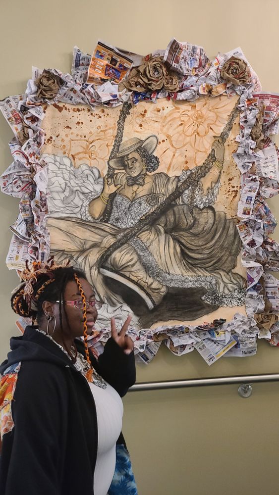 A large 4 ft by 4 ft drawing of me taking the place of the woman in the famous Jean-Honoré Fragonard painting "The Swing". Featuring my friend posing in the bottom left corner.

I have on a small hat with my curly hair tied into a bun in the back. I have bracelets, a cross necklace, and small hoop earrings as I dawn a large, flouncy dress. I am sitting on the swing, with one hand holding the rope and the other held up in a delicate pose.

 The background has large flowers with brown splotches littering the page. The palette is white, black, gold, and a very light brown. It was made with charcoal, coffee, and watercolor.

Most recent is the addition of a lot of newspaper as a backing and as a frame. There are also a few paper flowers with jewels in each center.