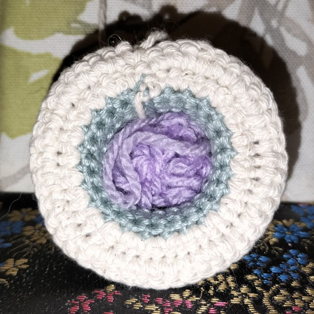 Top down view of crochet mushroom without cap. Off cuts of wool as stuffing.