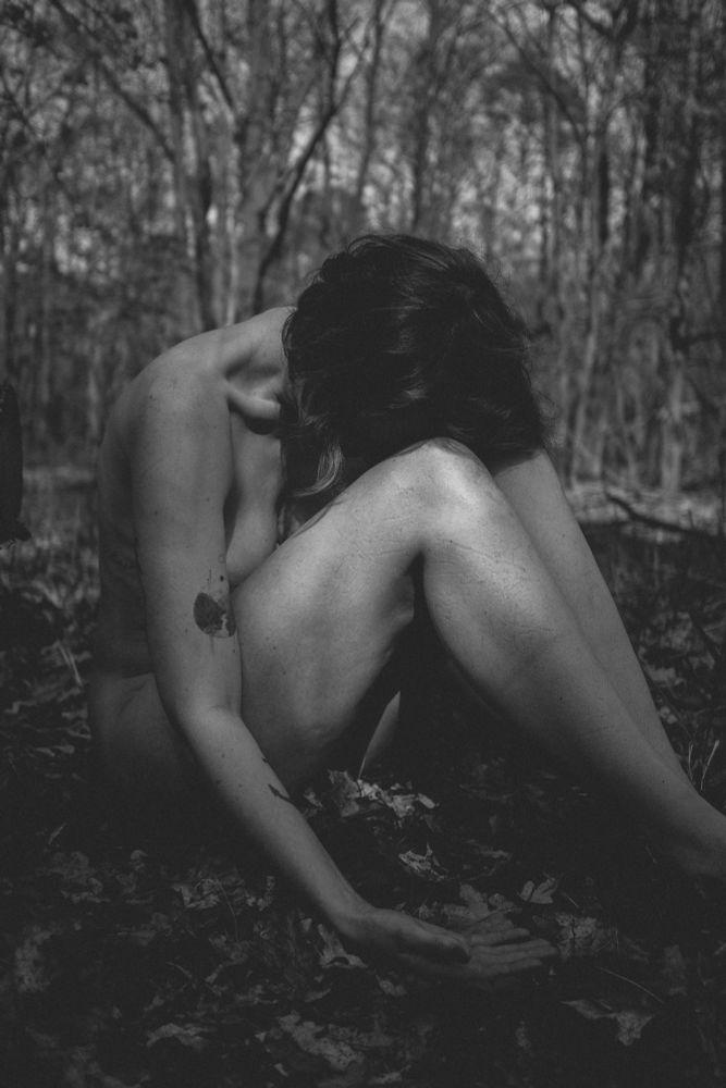 Nude woman sitting on the forest ground
