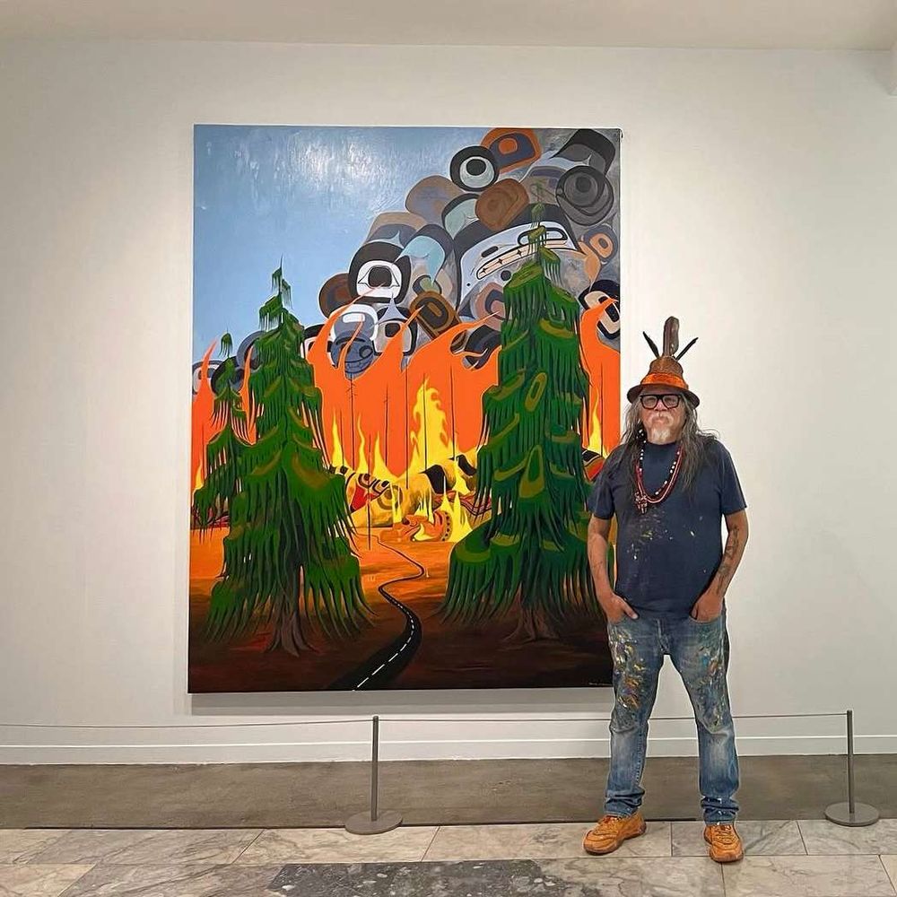 Artist Lawrence Paul Yuxweluptun Lets’lo:tseltun stands in front of his “The Impending Fire Storms” (2024) at the Vancouver Art Gallery.