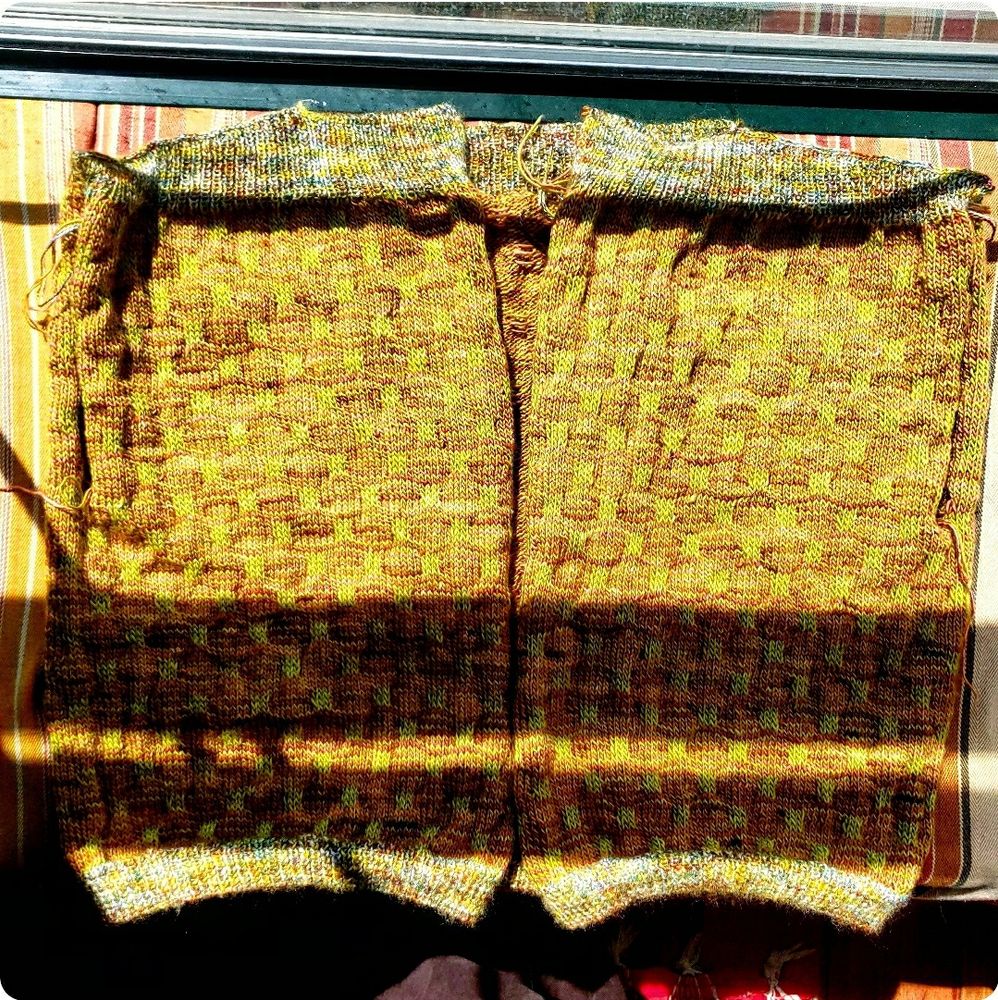 A green and orange colorwork cardigan in progress. 