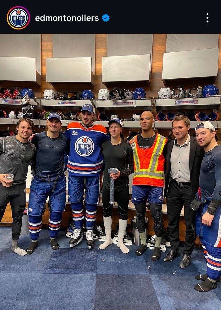 Darnell nurse in a high vis vest and ryan nugent-hopkins holding a large metal object that looks like the top part of those oil extraction things (they were calling it a wrench). They're also surrounding by like half the team