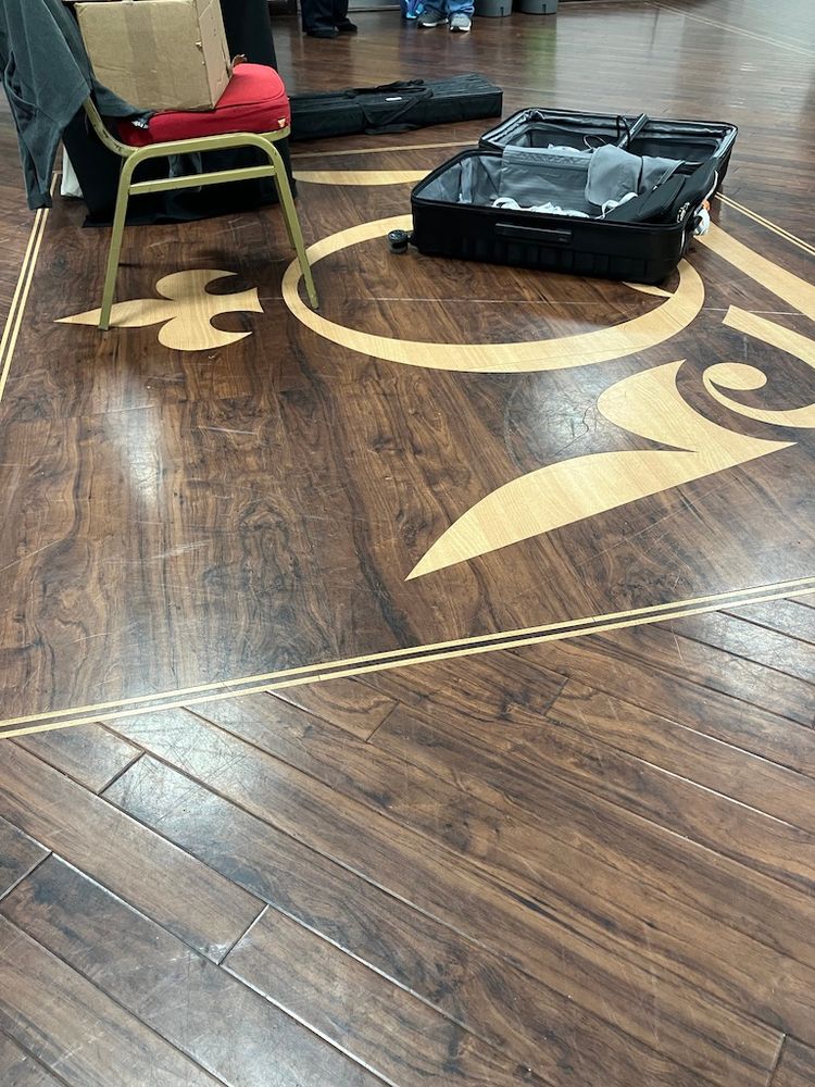A mildly arty shot of the wooden floor in the anteroom to the Octagon at QMUL which has our Q logo inlaid in a lighter coloured wood. On top of it is a suitcase which has transported some of the stuff we need to put signs up and make sure no-one gets lost. There are also boxes of magazines to give out and some pull-up banners waiting to be unpacked and set up.
