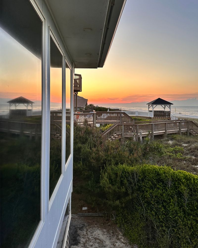 Sunrise and ocean reflected in cottage window. 
