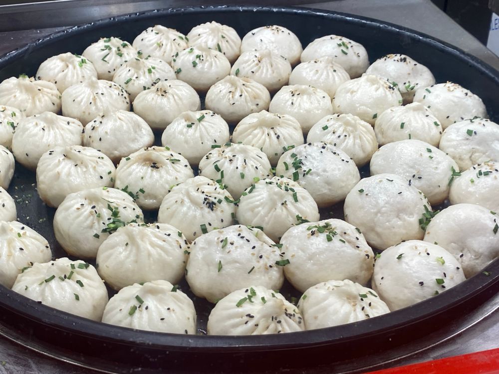 커다란 프라이팬에 만두 수십개가 놓여있는 사진