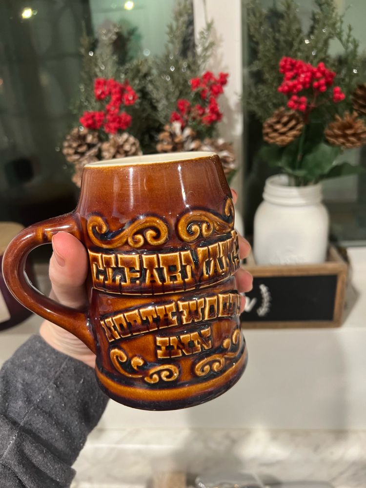 A brown tankard-style mug that says “Clearman’s North Woods Inn” on it.